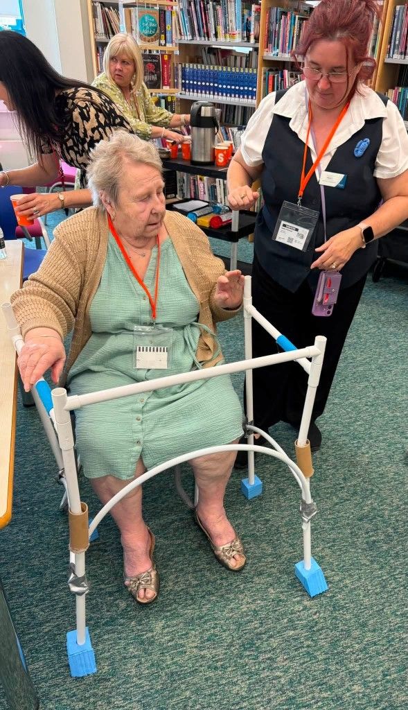 A Grace Court resident testing a student-built standing aid prototype, supported by Kinder Essex.
