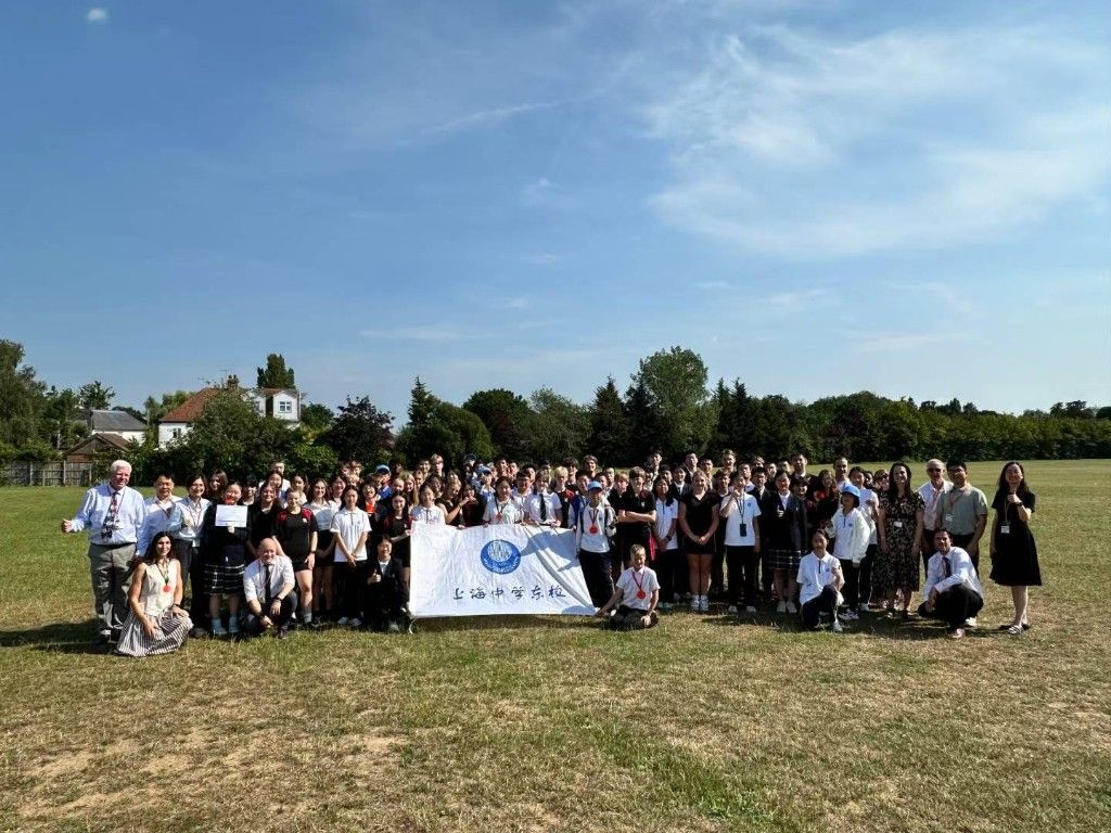 Students and staff from The King John School and East Shanghai High School standing together on the school field holding the East Shanghai High School banner, marking the Design for Life STEM Challenge.
